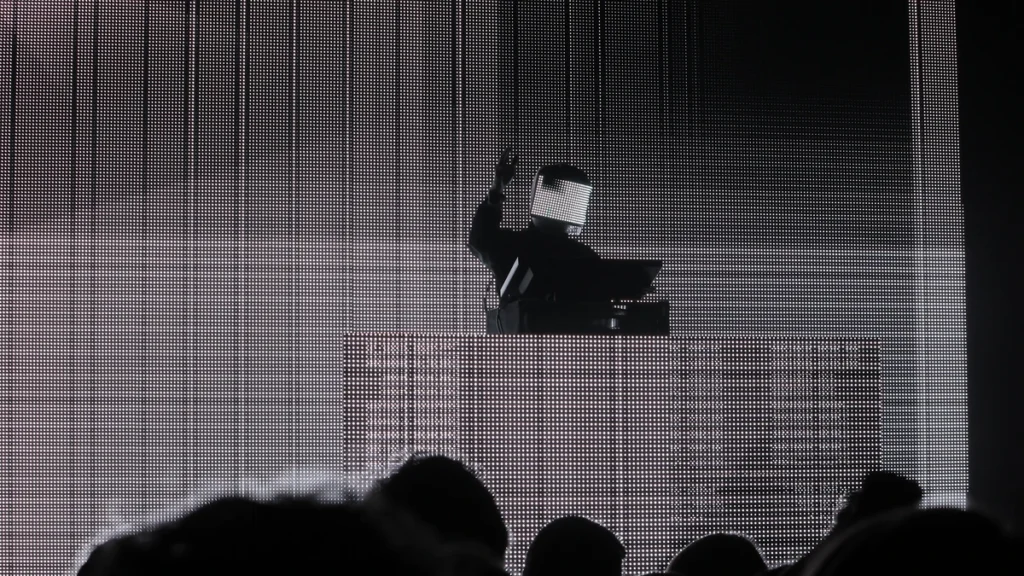 Squarepusher performing in an LED visor mask in front of a large screen