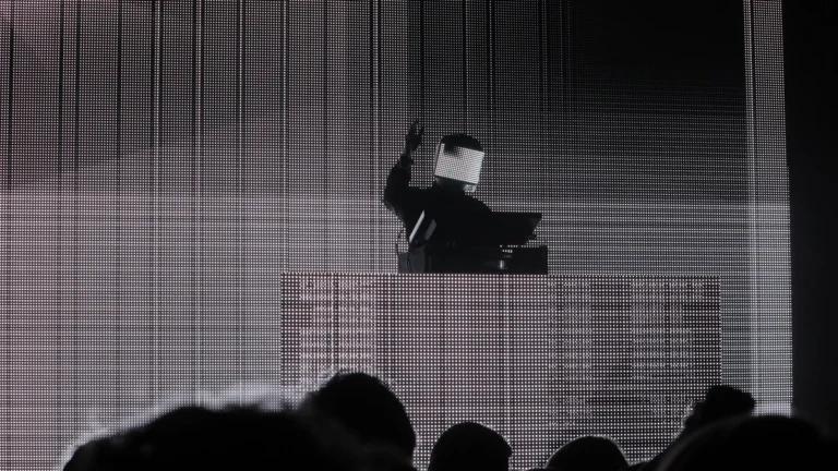 Squarepusher performing in an LED visor mask in front of a large screen