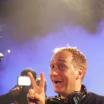Paul van Dyk performing with headphones under stage lighting