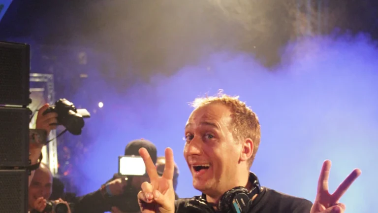 Paul van Dyk performing with headphones under stage lighting