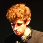 Jamie xx wearing headphones behind a mixer