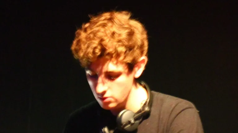 Jamie xx wearing headphones behind a mixer
