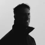 Boys Noize, Alex Ridha, in a black and white portrait against a pale background